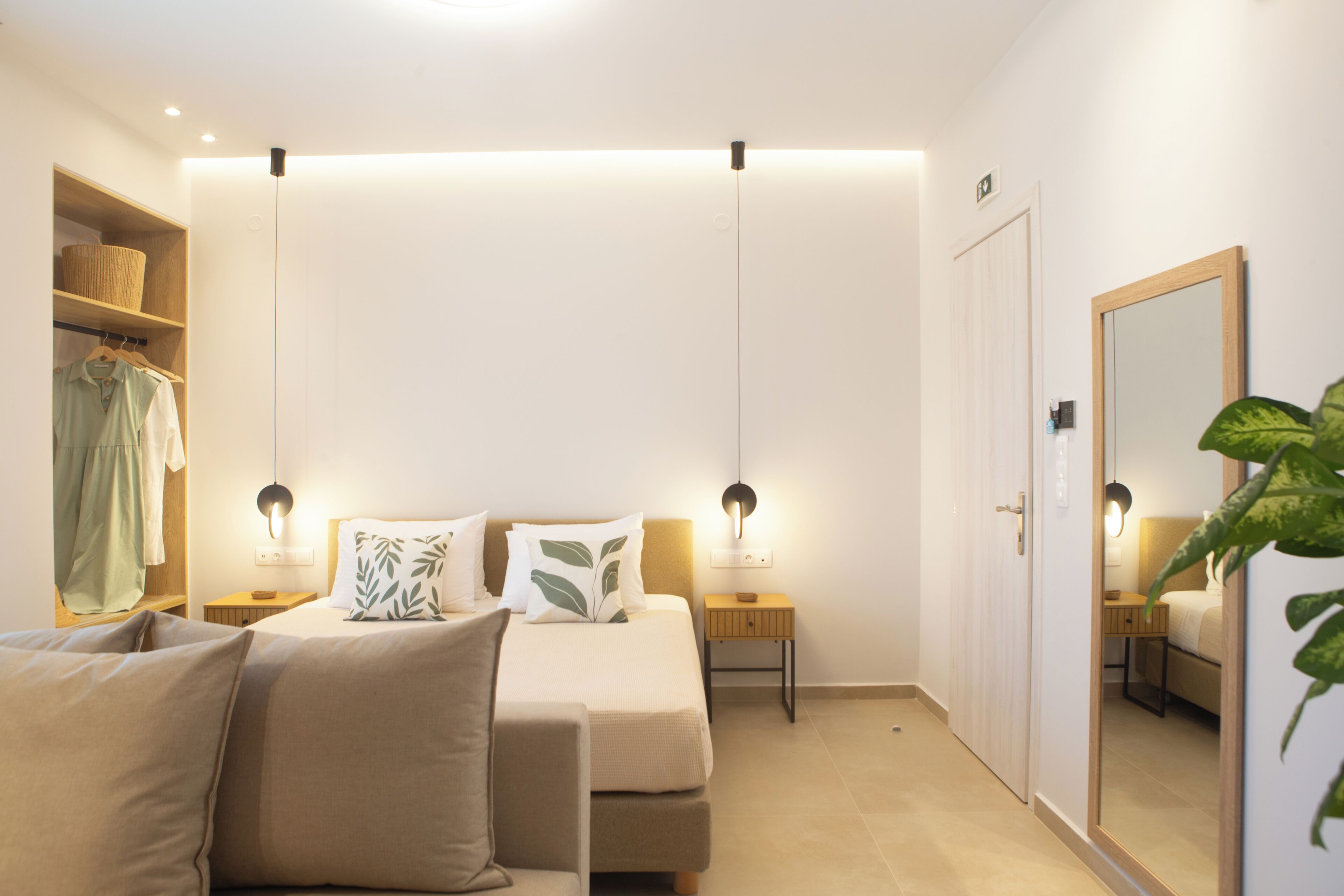 Hotellihuone, jossa on sänky, yöpöydät, vaatekaappi ja peili.