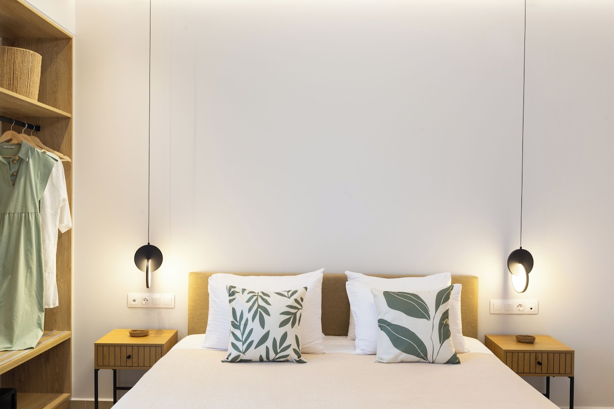 A neatly arranged bedroom with a bed, two bedside tables, a hanging light fixture, and a wardrobe.