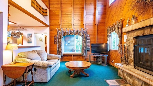 A cozy cabin interior with a fireplace, a television, and a comfortable seating area. - Paradise Found (Davis)