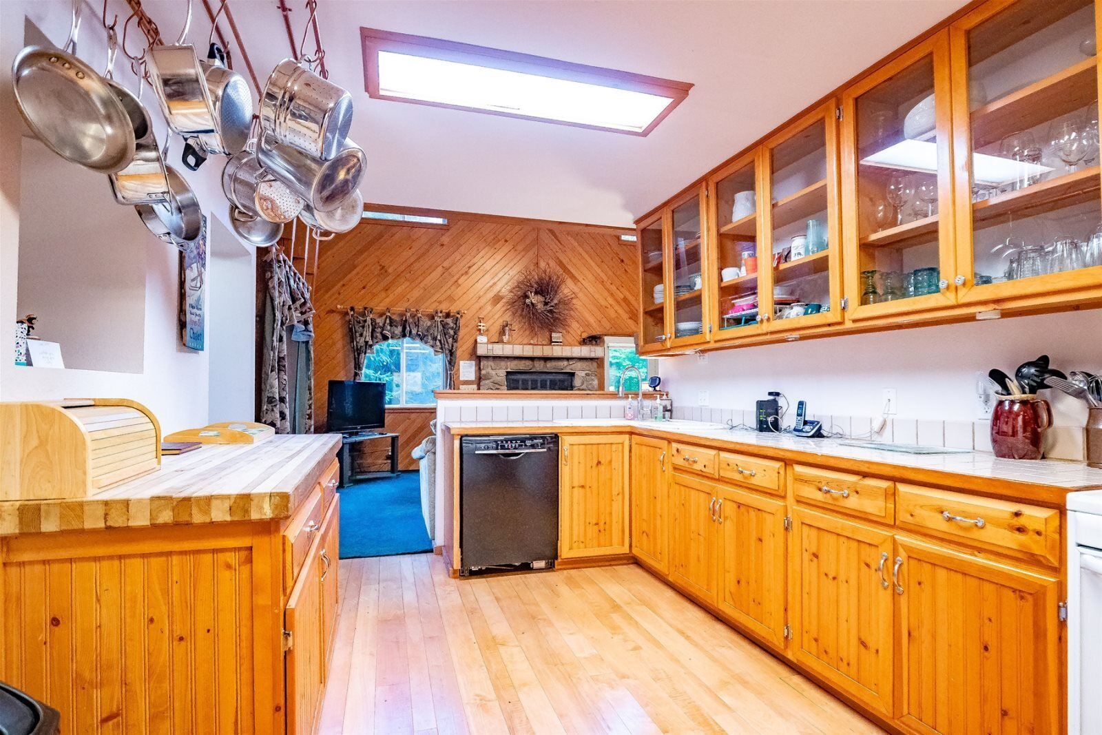 A kitchen with wooden cabinets, a dishwasher, and a dining area with a wooden table and chairs.