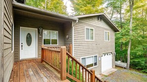 A two-story house with a wooden deck and a front door. - Paradise Found (Davis)
