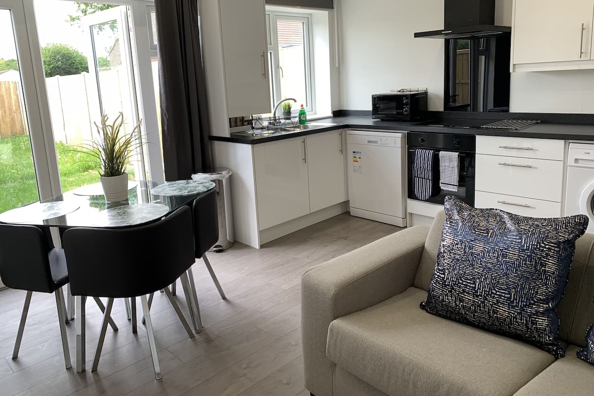 A modern kitchen with a dining area, a sofa, and a view of the garden.