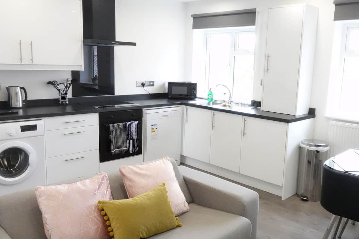 A compact kitchen with a washing machine, microwave, and a sink.
