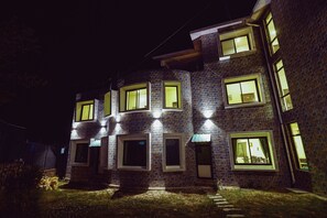 A multi-story building with illuminated windows and a brick facade. - Hotel Sagarmatha (Baijnath)