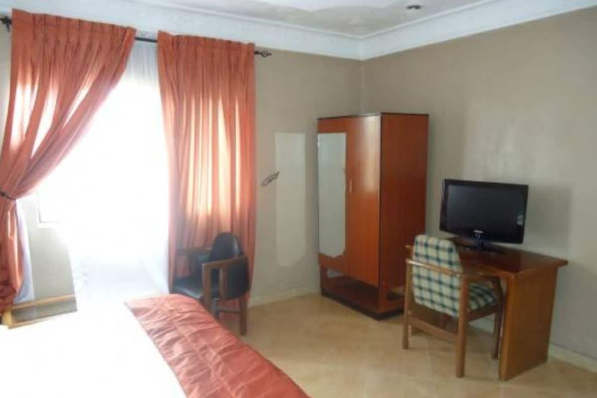 Una habitación de hotel con cama, escritorio, silla, armario y televisión.