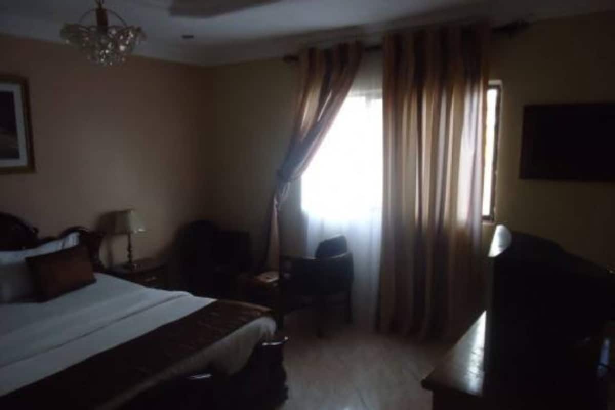 Una habitación de hotel con cama, escritorio, silla, televisor y cortinas.