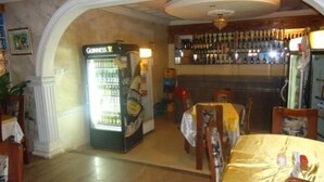 A bar area with a Guinness refrigerator, a bar counter, and a dining area with a table and chairs. - Meridian Lodge hotels & resorts (Benin City)