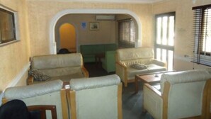 A room with a high ceiling, a green sofa, a beige sofa, and a wooden coffee table. - Meridian Lodge hotels & resorts (Benin City)