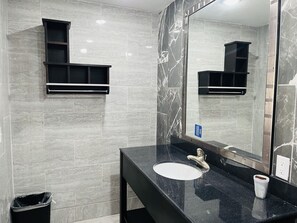 A bathroom with a black countertop, a white sink, a mirror, and a trash bin. - Town House Motel (Bay City)