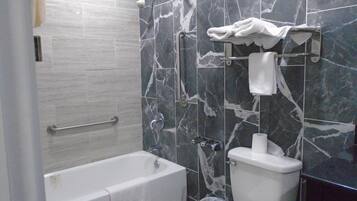A bathroom with a bathtub, toilet, and a shower area.