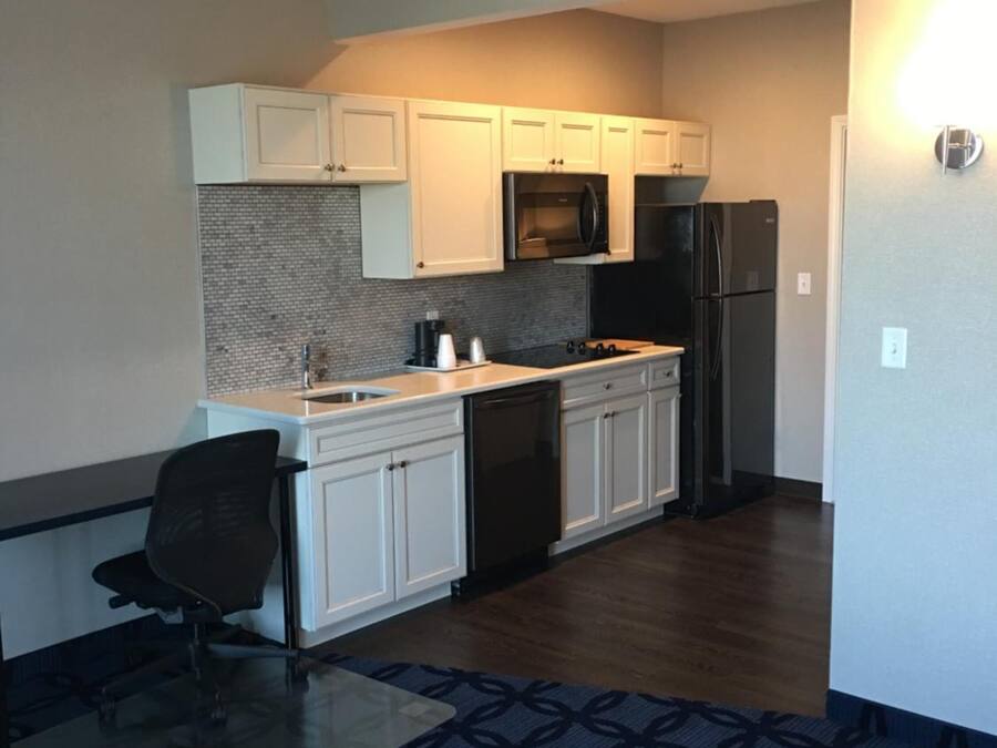 A compact kitchen with white cabinets, a microwave, a refrigerator, and a dishwasher.