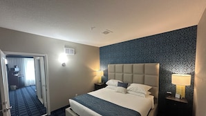 A hotel room with a bed, two bedside lamps, a headboard, and a patterned carpet.