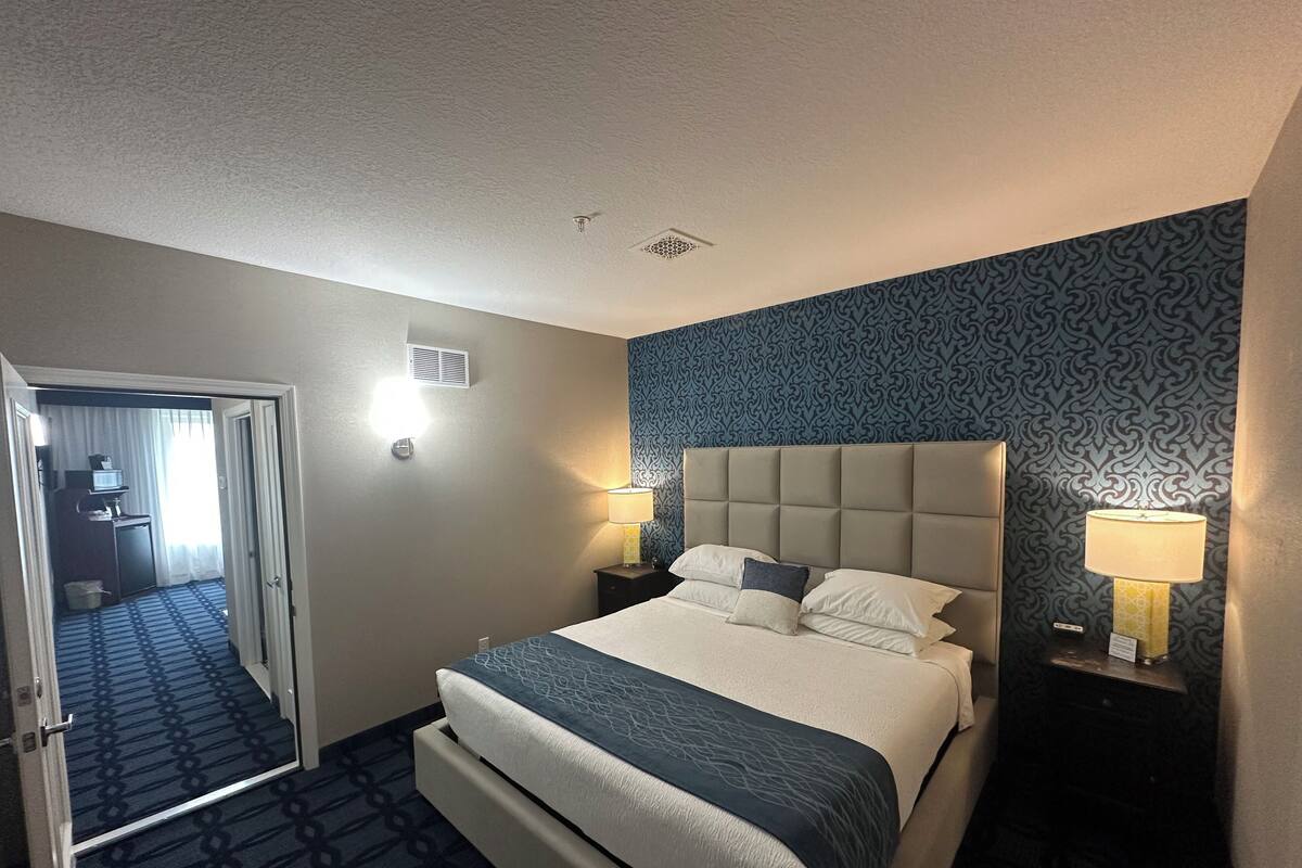 Ett hotellrum med en säng, två sänglampor, en sänggavel och en mönstrad matta.
