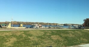 A waterfront area with a grassy embankment, a small tower, and a dock with boats.