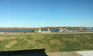 A riverside view with a grassy area, a small building, and a dock with boats.