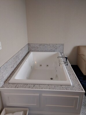 A modern bathroom with a freestanding bathtub, white tiled walls, and a black and white patterned tile border.