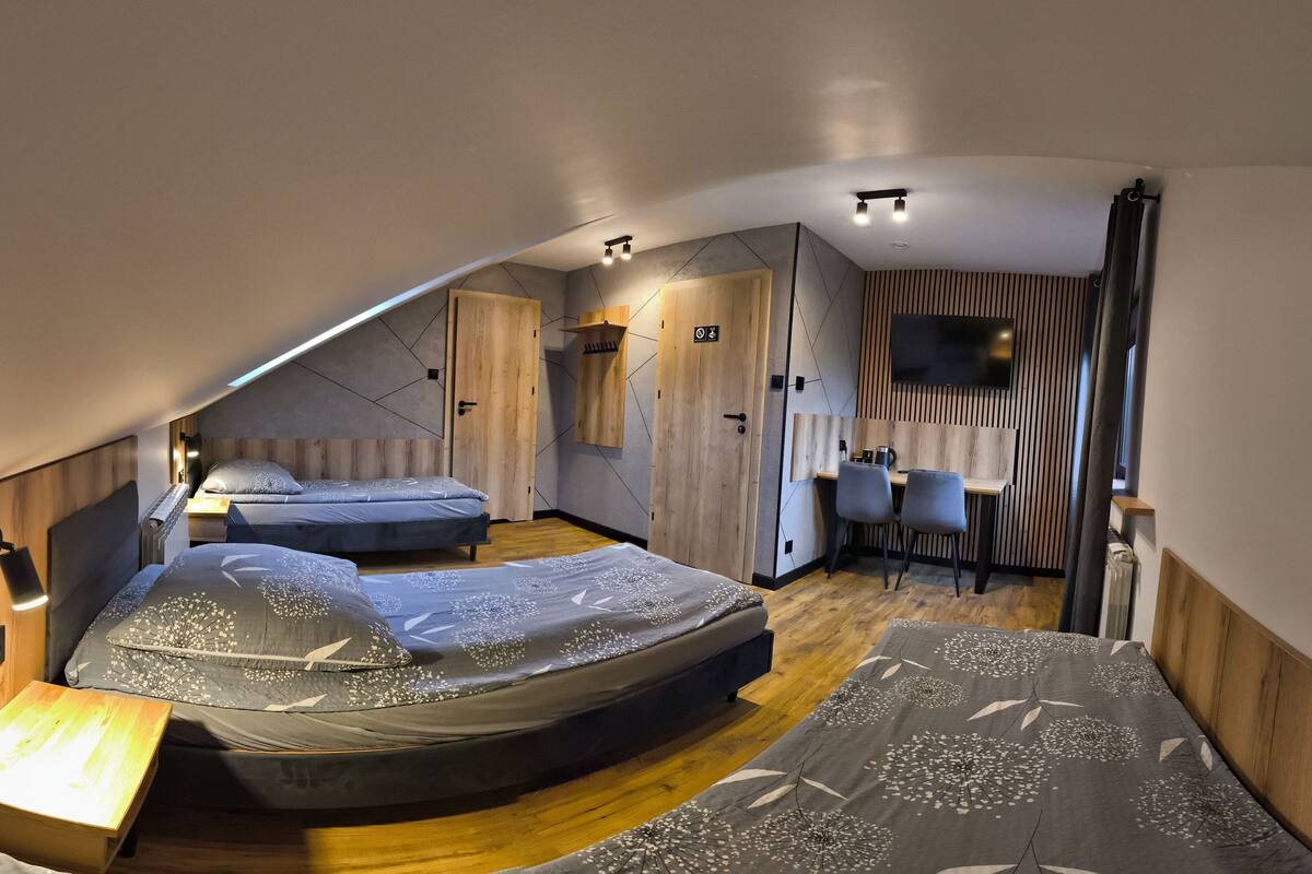 A compact, modern room with two beds, a desk, and a seating area.