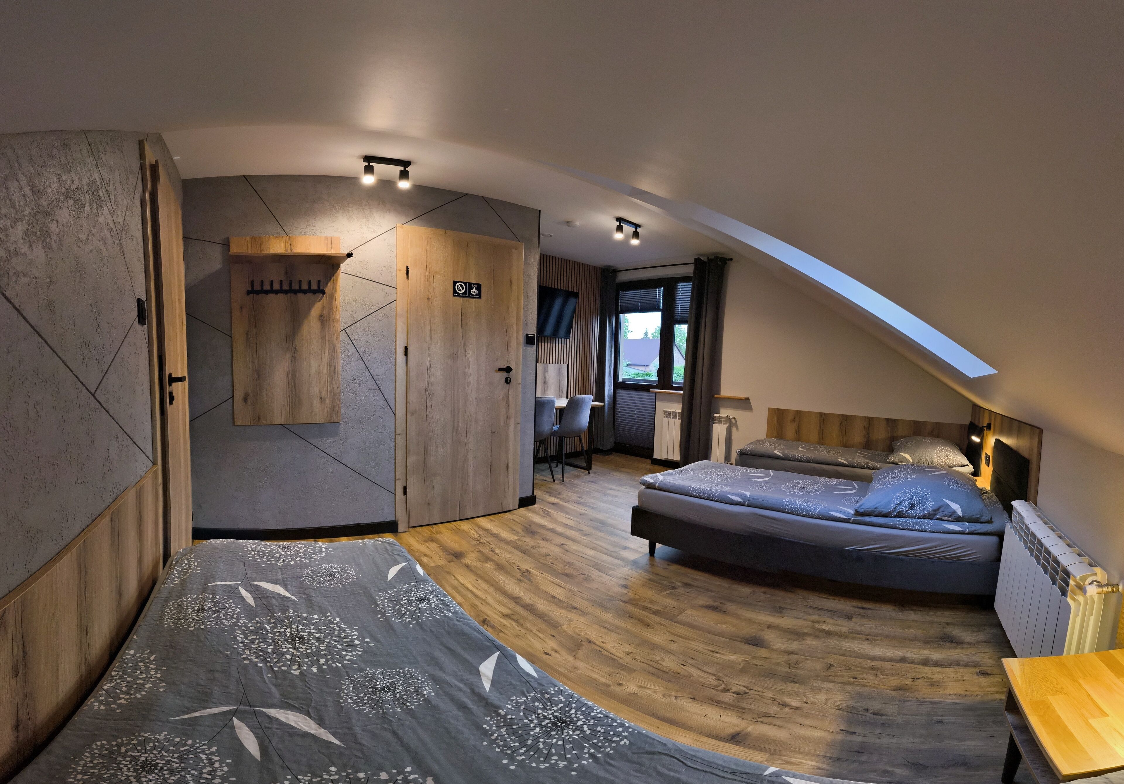 A modern bedroom with a loft bed, a wooden wardrobe, a desk, and a view of the outdoors.