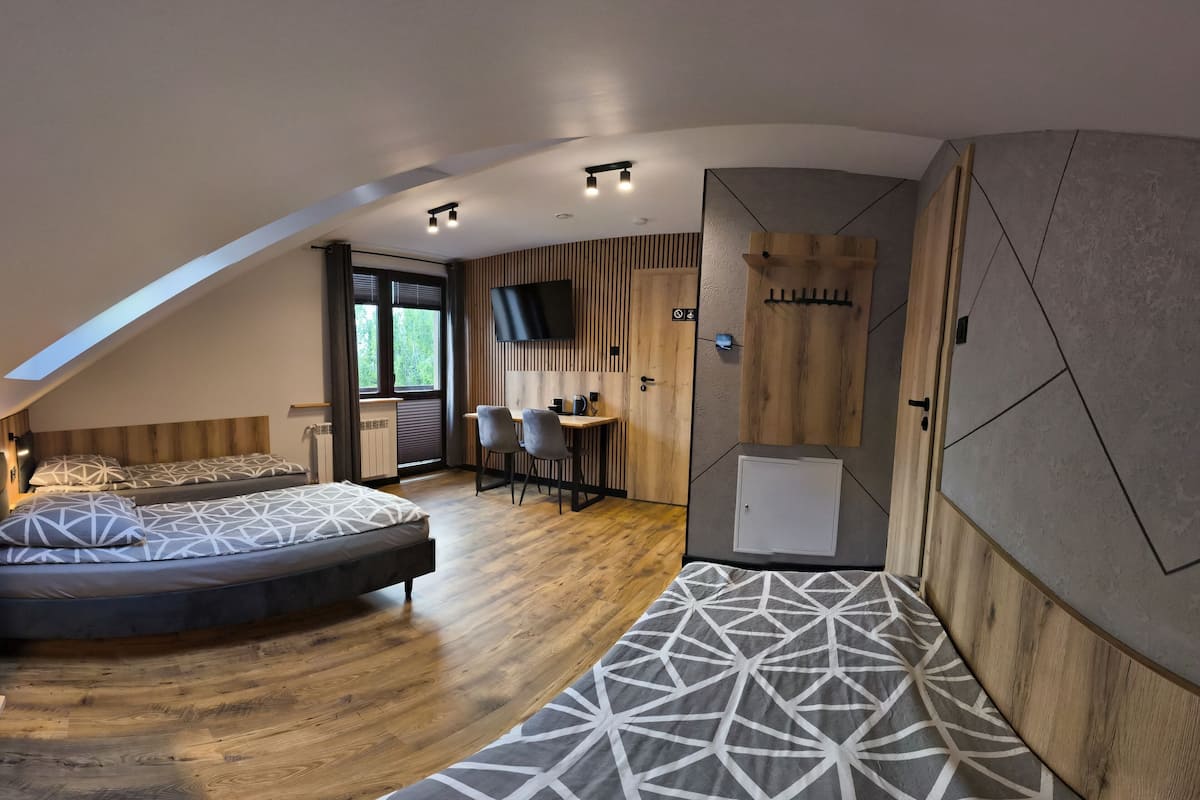 A modern loft bedroom with a curved ceiling, a bed, a desk, and a shower area.