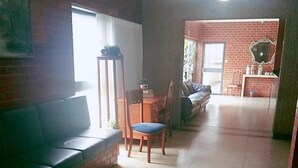 A living room with a sofa, a dining table with chairs, and a kitchen area in the background. - Goias Hotel (Goiania)