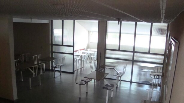 A spacious dining area with tables and chairs, large windows, and a high ceiling. - Goias Hotel (Goiania)