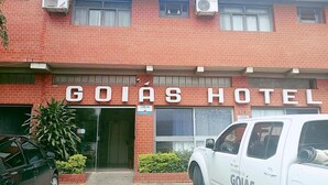 A hotel named GOIAS HOTEL with a brick facade, air conditioning units, and a white van parked in front. - Goias Hotel (Goiania)