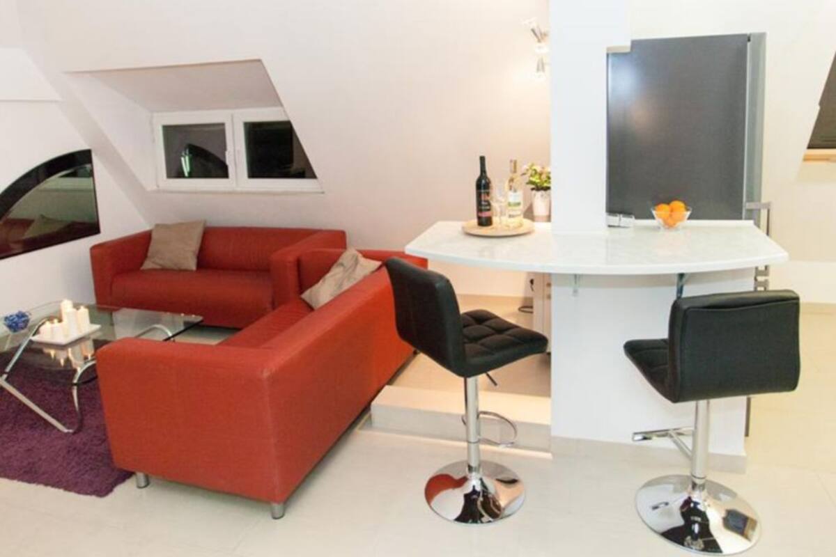 A modern living room with a red sofa, black chairs, a white table, and a TV.