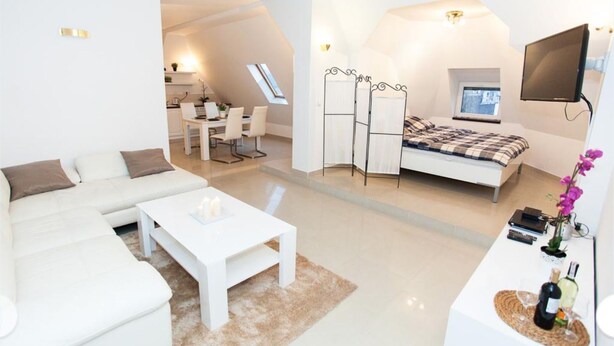 A modern, well-lit living room with a sofa, coffee table, and a dining area with a table and chairs. - Studio Apartament Centrum Katowice (Katowice)