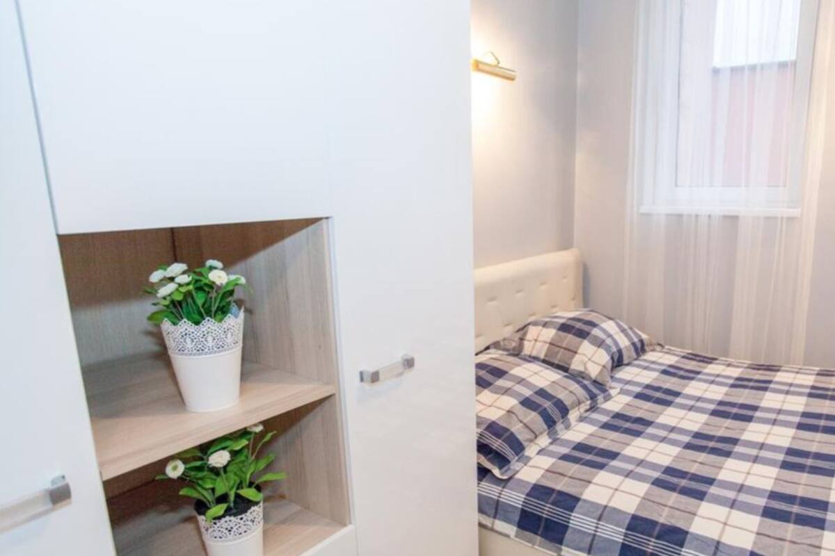 A bedroom with a bed, a bedside table, and a window with curtains.