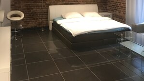 A modern bedroom with a brick wall, a white bed, and a glass table. - Studio Apartament Centrum Katowice (Katowice)