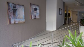 A modern interior with a staircase, metal railings, and abstract wall art. - Presidente Hotel - Passos (Passos)