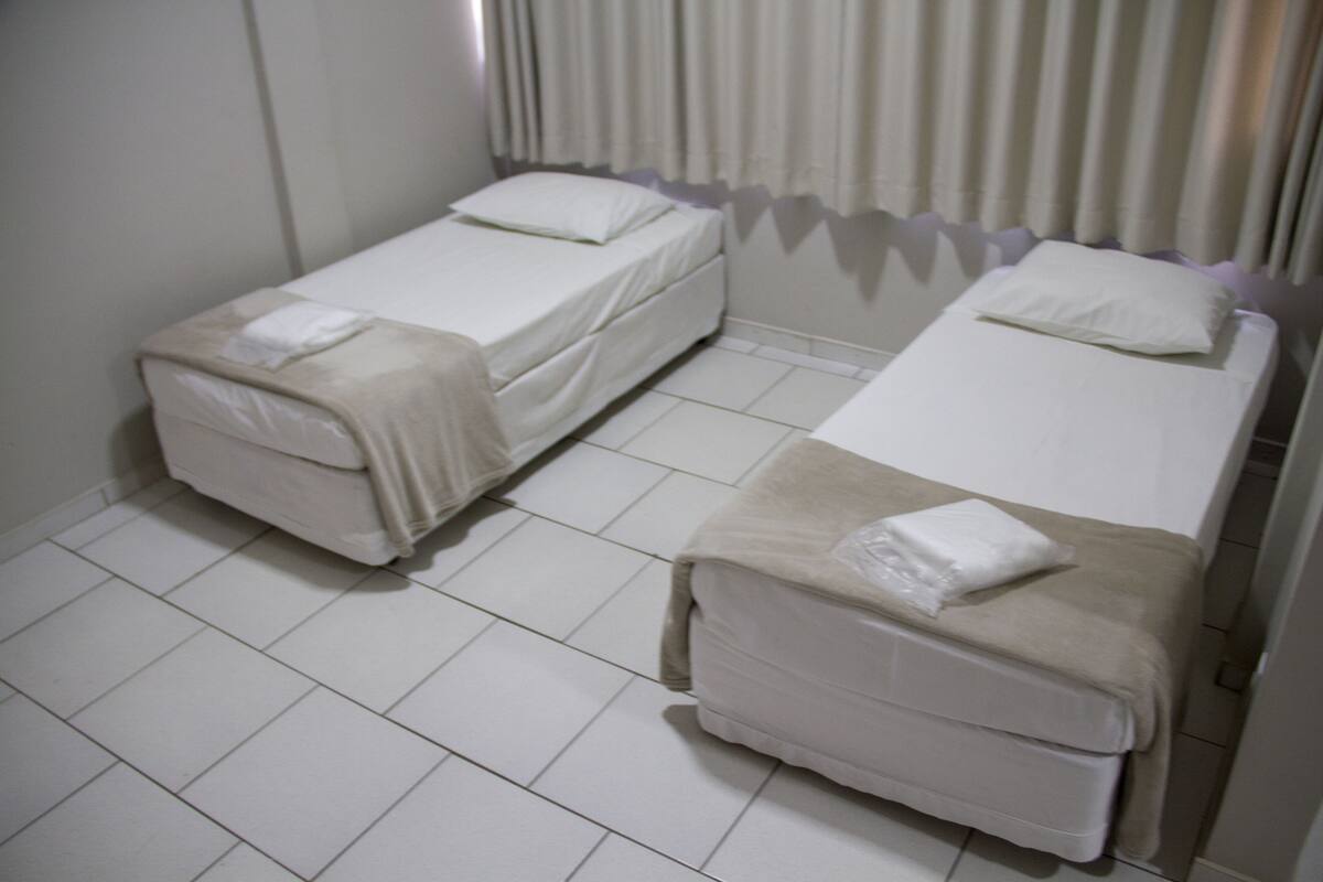 Una habitación con dos camas individuales, cada una con almohada y manta.