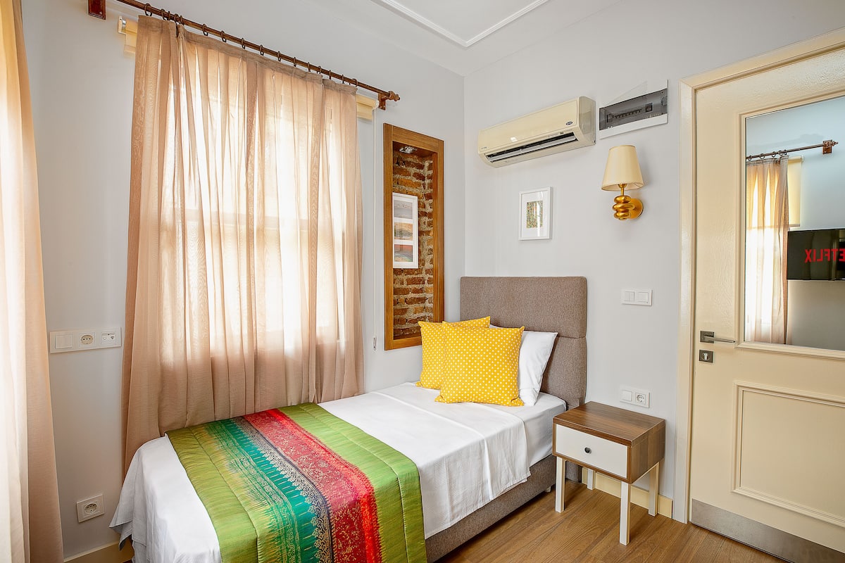 Une chambre bien rangée, avec un lit, une table de chevet et une porte.