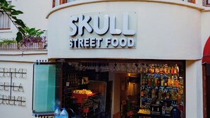 A storefront with a sign reading "SKULL STREET FOOD" and a variety of bottles and glasses displayed outside. - Mono Hotel (Antalya)