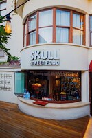 Un escaparate con un letrero que dice "SKULL STREET FOOD" y una variedad de botellas y vasos exhibidos en el exterior.
