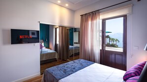 A hotel room with a bed, a TV mounted on the wall, a window with curtains, and a view of the outdoors. - Mono Hotel (Antalya)