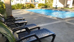 A poolside area with lounge chairs and a swimming pool. - Tropical Condo BBQ Pool 5min to Airport (Puñal)