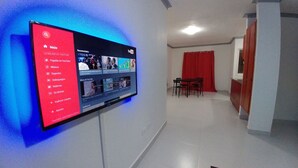A flat-screen TV mounted on a wall displaying YouTube content. - Tropical Condo BBQ Pool 5min to Airport (Puñal)