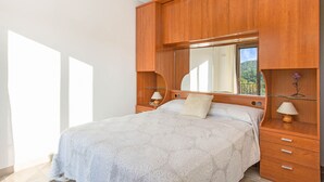Un dormitorio con una cama grande, cabecera de madera, lámparas de noche y un espejo.