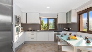 Una cocina moderna con armarios blancos, una mesa de comedor con sillas y vistas al exterior.