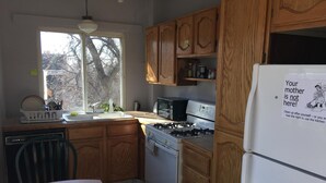 Une cuisine avec des meubles de rangement en bois, une cuisinière, un four à micro-ondes et un réfrigérateur.