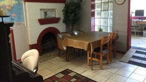 Un coin repas comprenant une table, des chaises, une cheminée, une carte accrochée au mur et une horloge.