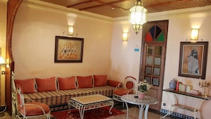 A traditional room with a sofa, chairs, a small table, and a decorative door. - Hotel Royal (Oujda)