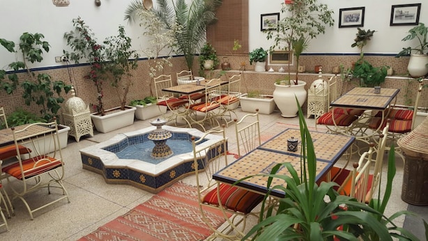 A traditional Moroccan-style interior with tiled flooring, a central fountain, and various seating arrangements including chairs and tables. - Hotel Royal (Oujda)