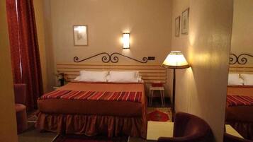 A hotel room with a large bed, two wall sconces, a nightstand, a chair, and a mirror.