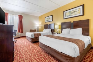 A hotel room with two beds, a desk, a chair, a TV, and a window with curtains. - Quality Inn Lexington (Lexington)