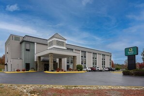 A Quality Inn & Suites hotel with a covered entrance, multiple parking spaces, and a clear sky. - Quality Inn Lexington (Lexington)
