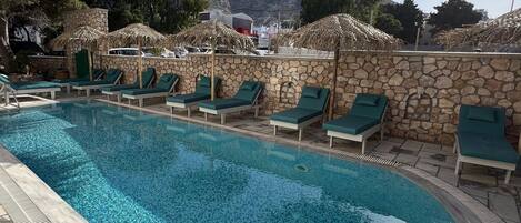 Une piscine avec des chaises longues et un mur en pierre.