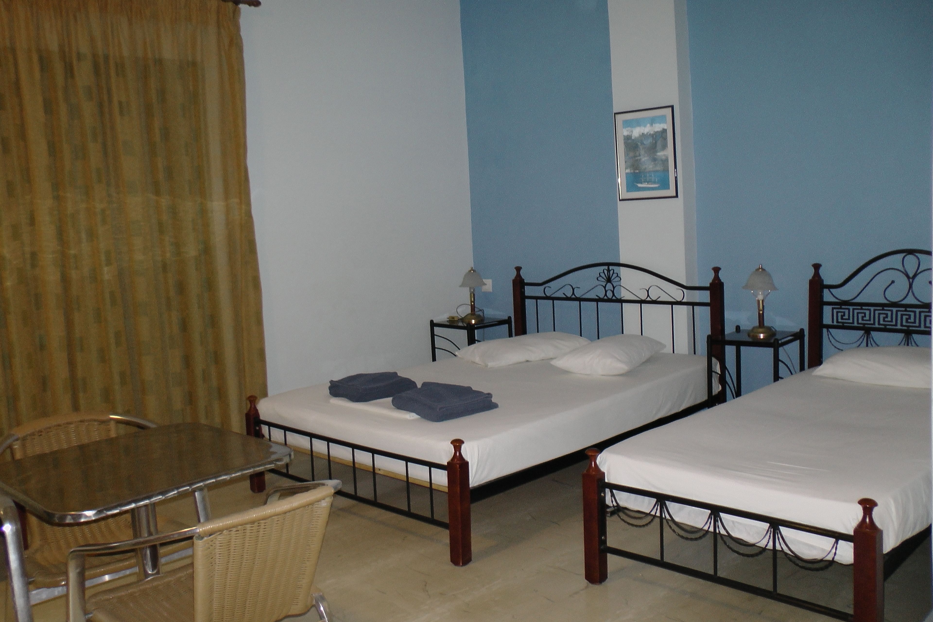 A room with two single beds, a small table, and a chair.