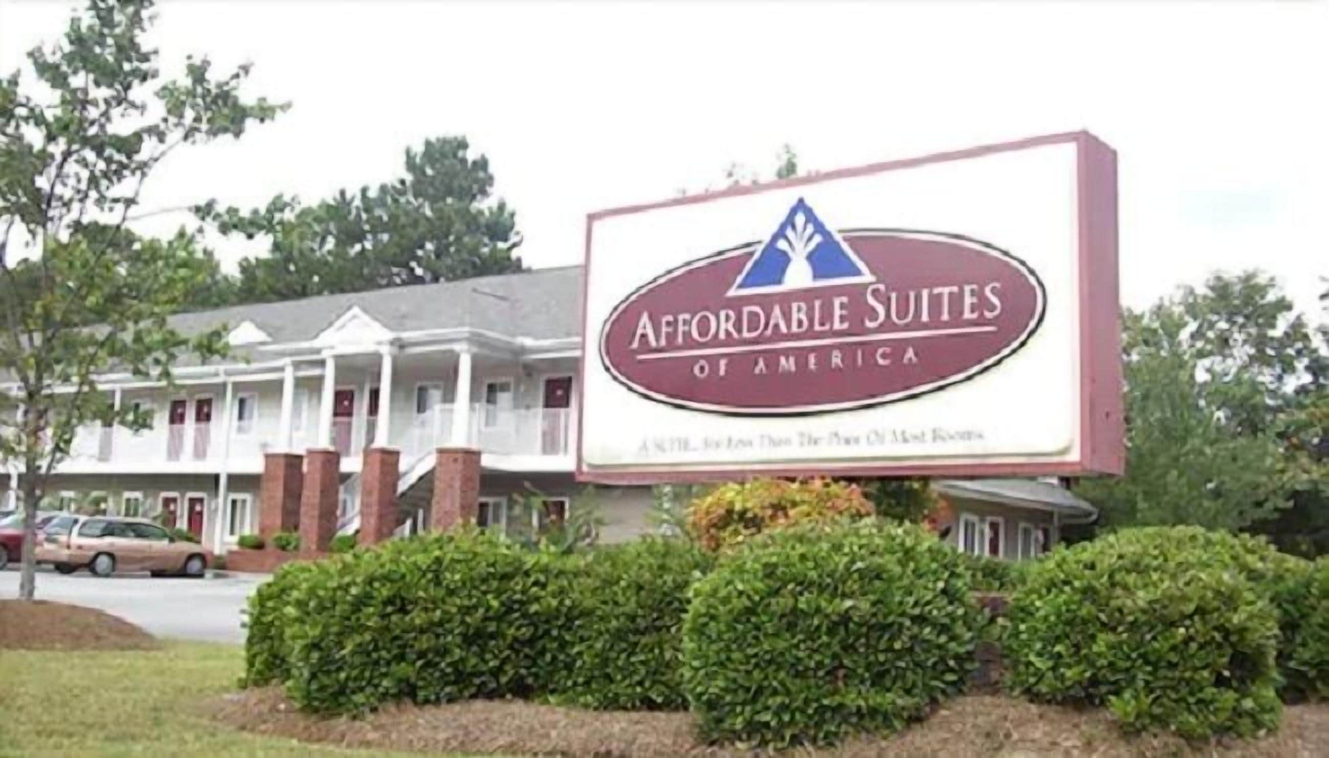 Letrero de Affordable Suites of America, mostrando un edificio tradicional con porche y columnas de ladrillo.